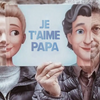 Un Papa et sa fille en train de jouer avec la couverture du livre pour papa, sur laquelle il apparaît avec son enfant adulte. La ressemblance est saisisante.