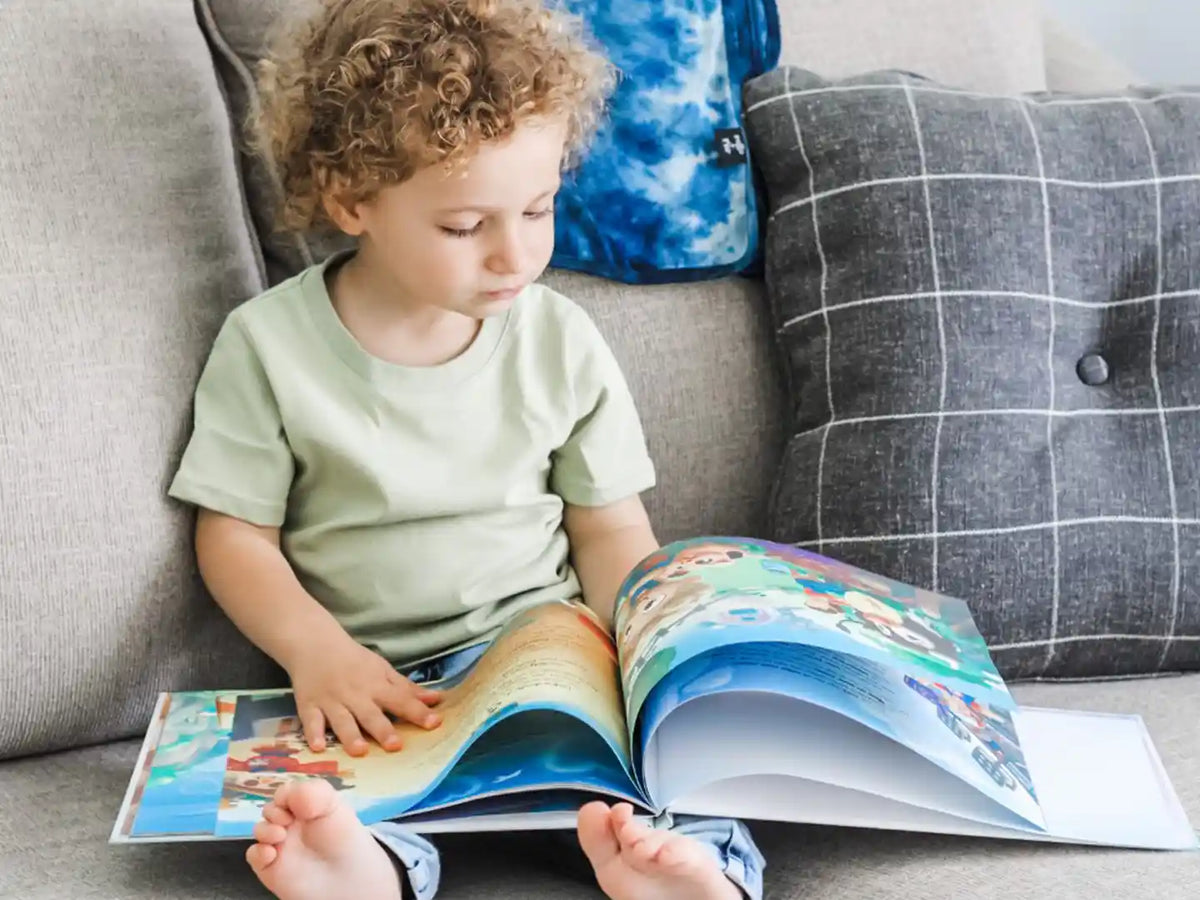 Un enfant découvrant son livre personnalisé sur les métiers qu'il a reçu comme cadeau de Noël.