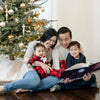 Une famille lisant son livre perosnnalisé de Noël sous le sapin.