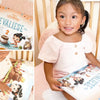 Une petite fille souriante de deux ans avec son livre d'anniversaire personnalisé.