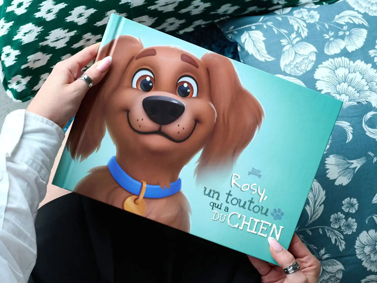 Person tenant le livre pour chien « Rosy, lun toutou qui a DU CHIEN » avec un mignon chien en dessin animé sur la couverture.