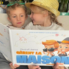 Un frère et une sœur tenant leur nouveau livre personnalisé sur le fait d'être seuls à la maison.