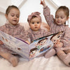 Trois petites soeurs sont en train de feuilletter le meilleur livre personnalisé pour fratries de chez Hourra Héros.