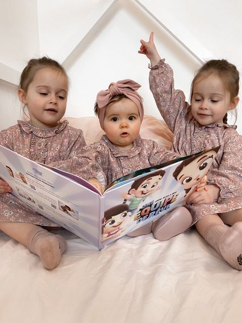 Trois petites soeurs sont en train de feuilletter le meilleur livre personnalisé pour fratries de chez Hourra Héros.