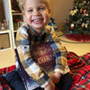 Ce petit garçon sourit car il a reçu comme cadeau de Noël un livre personnalisé.