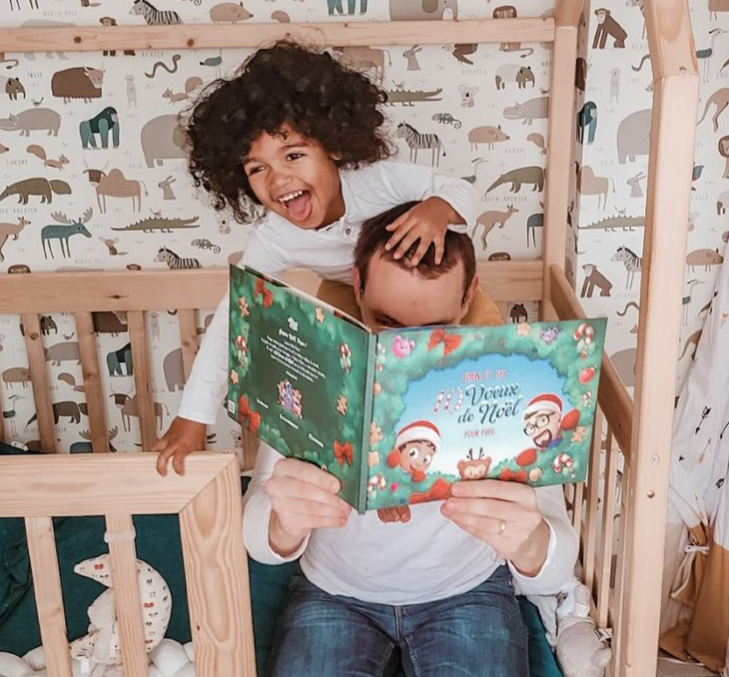 Papa et son enfant lisant leur livre personnalisé de Noël Hourra Héros.