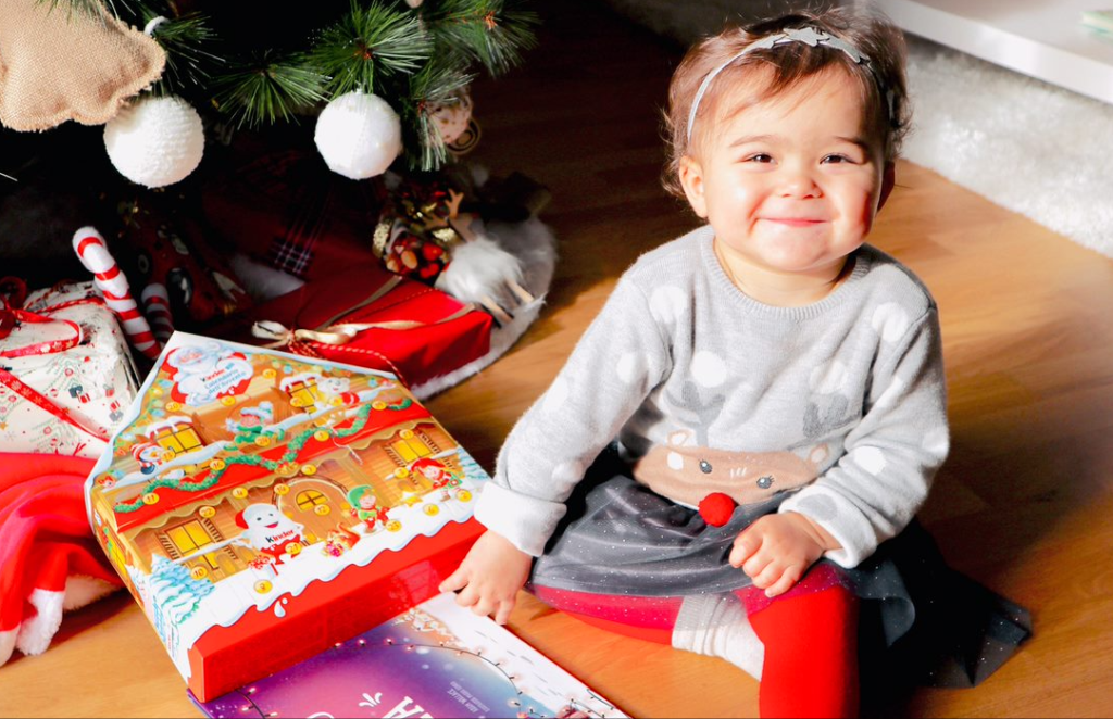 Petite fille heureuse avec son livre personnalisé de Noël Hourra Héros.